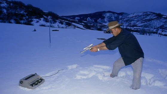 Hunter S. Thompson takes aim at a typewriter.